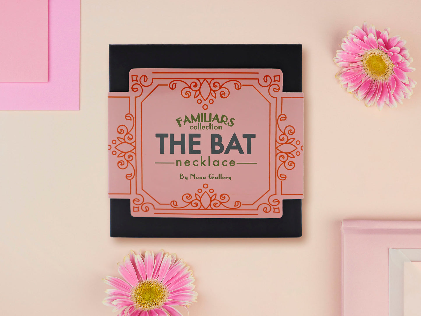 A wooden and glitter acrylic necklace with gold chain in a black box of four cute bats hung upside down on a cave wall of stalactites