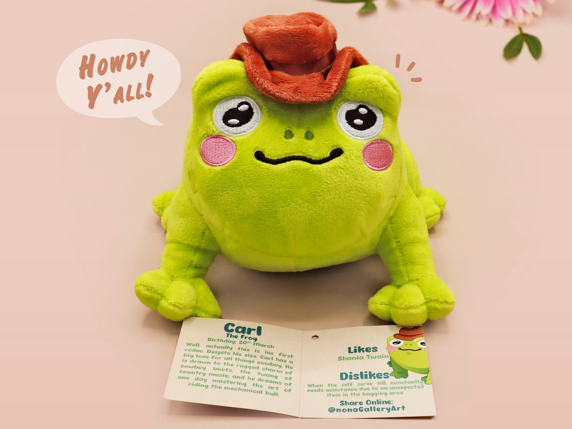 An adorable green frog plushie toy with cute embroidered eyes and facial expression, wearing a cowboy hat with a brown ribbon, and a hang tag describing the frog as Carl.