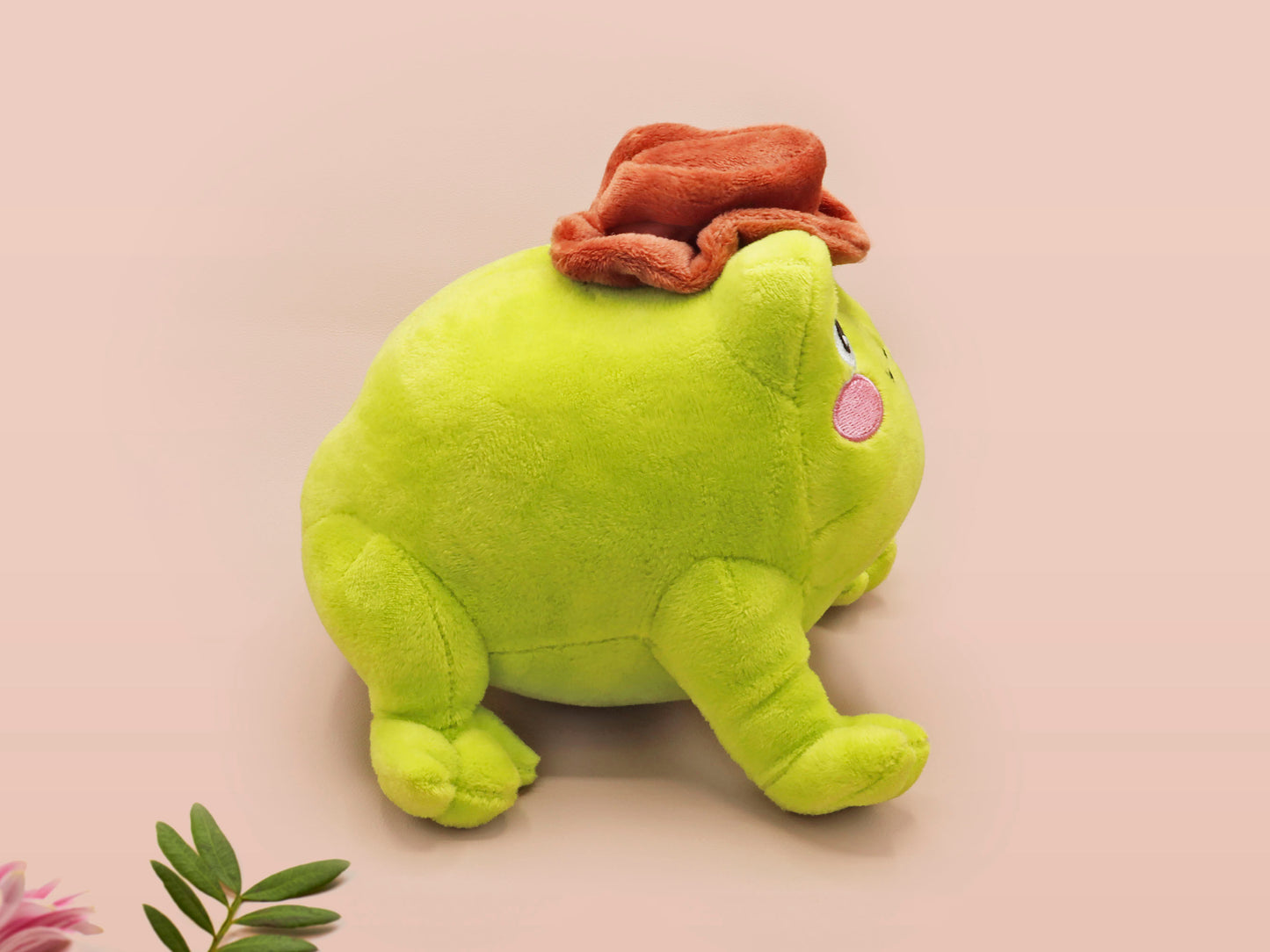 An adorable green frog plushie toy with cute embroidered eyes and facial expression, wearing a cowboy hat with a brown ribbon, and a hang tag describing the frog as Carl.