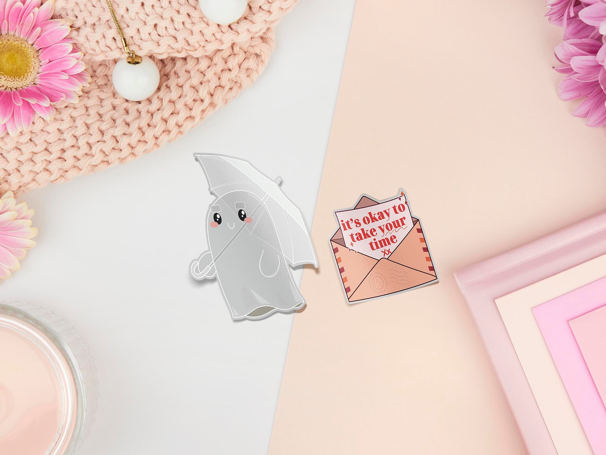 Two stickers of illustrated cartoon ghost with an umbrella and a letter in an envelope that reads it's okay to take your time
