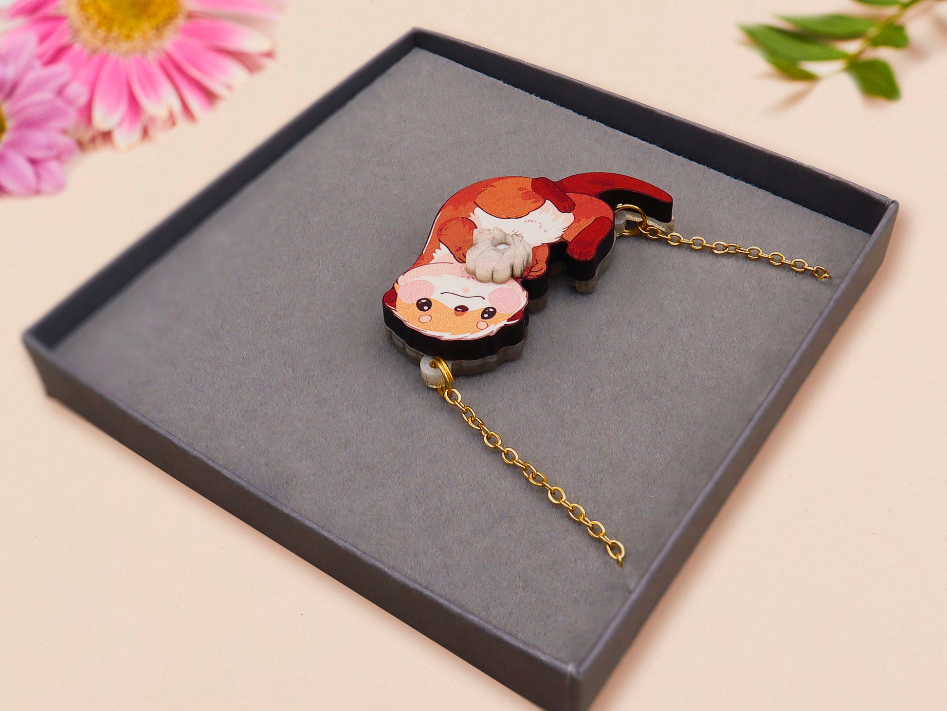 An adorable cute otter holding a clam seashell with a pearl inside necklace made of wood and glitter pearlescent acrylic with a gold chain is displayed in a velvet gift box with a unique cute otter sleeve design.