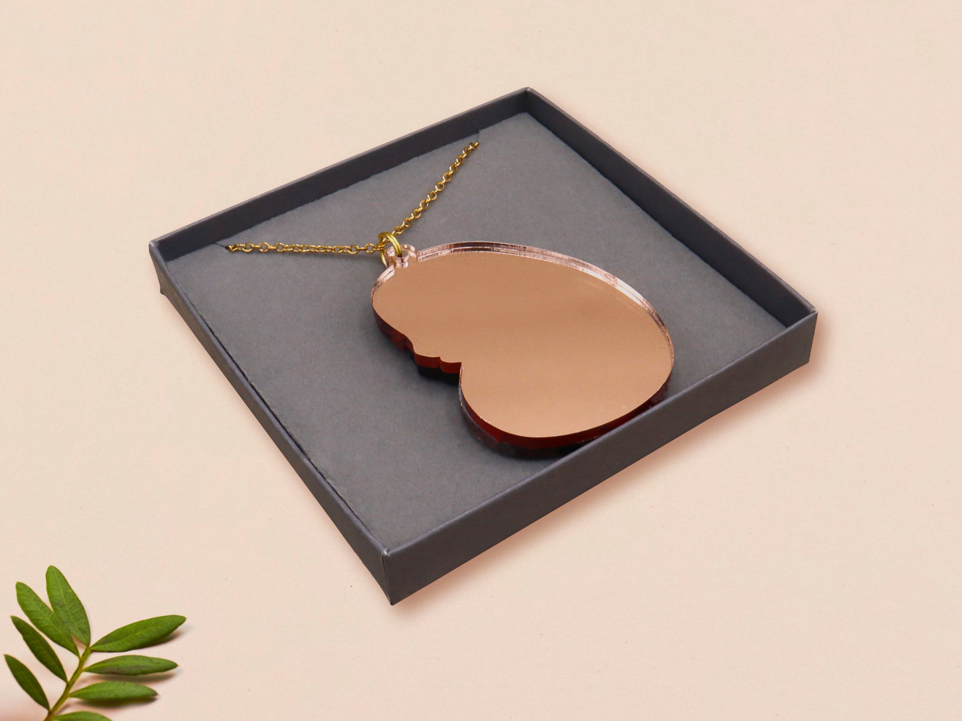 An adorable shy pangolin aardvark holding a heart necklace made of wood and glitter mirror acrylic with a gold chain is displayed in a velvet gift box with a unique cute Pangolin sleeve design.