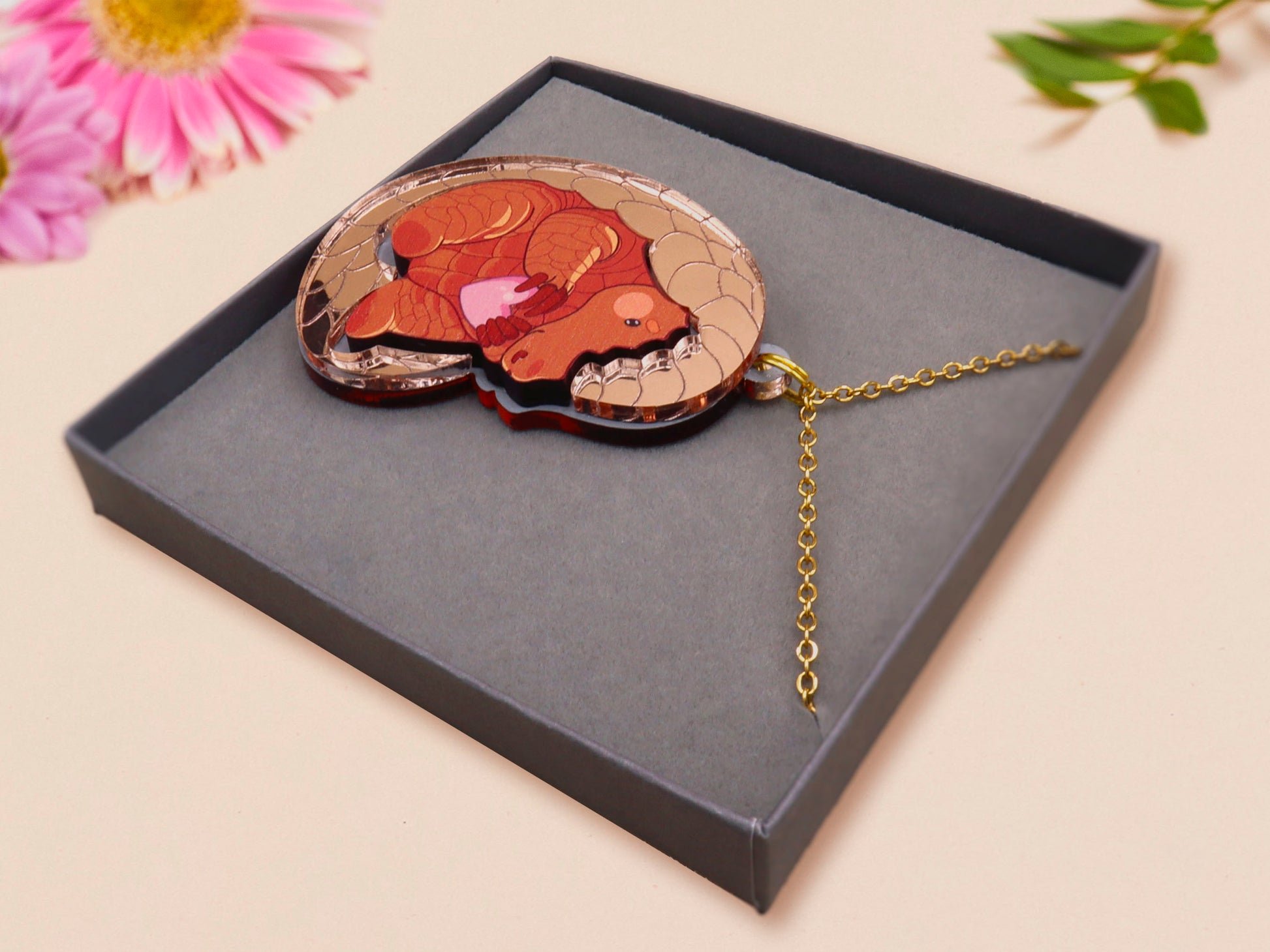 An adorable shy pangolin aardvark holding a heart necklace made of wood and glitter mirror acrylic with a gold chain is displayed in a velvet gift box with a unique cute Pangolin sleeve design.
