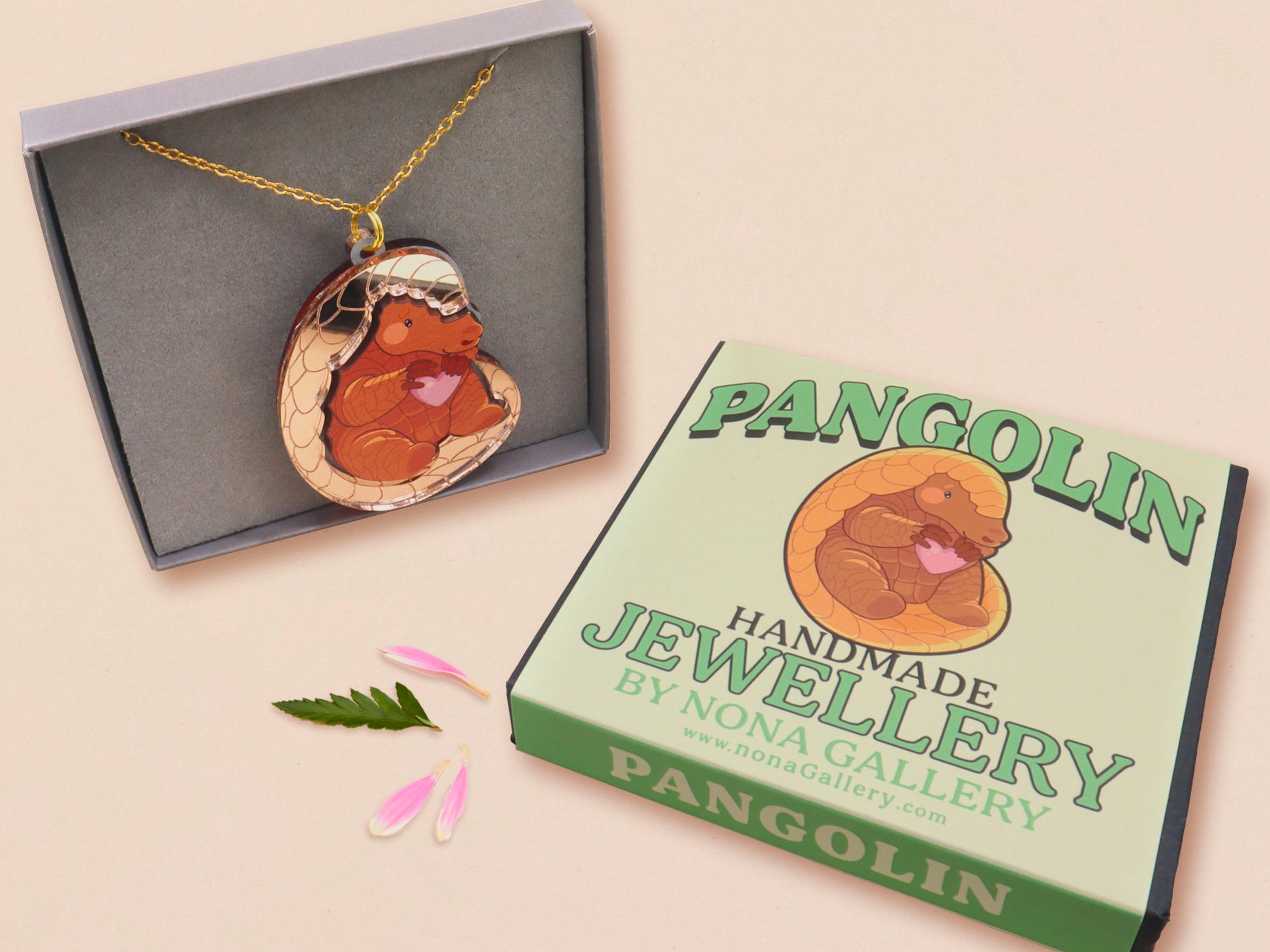 An adorable shy pangolin aardvark holding a heart necklace made of wood and glitter mirror acrylic with a gold chain is displayed in a velvet gift box with a unique cute Pangolin sleeve design.