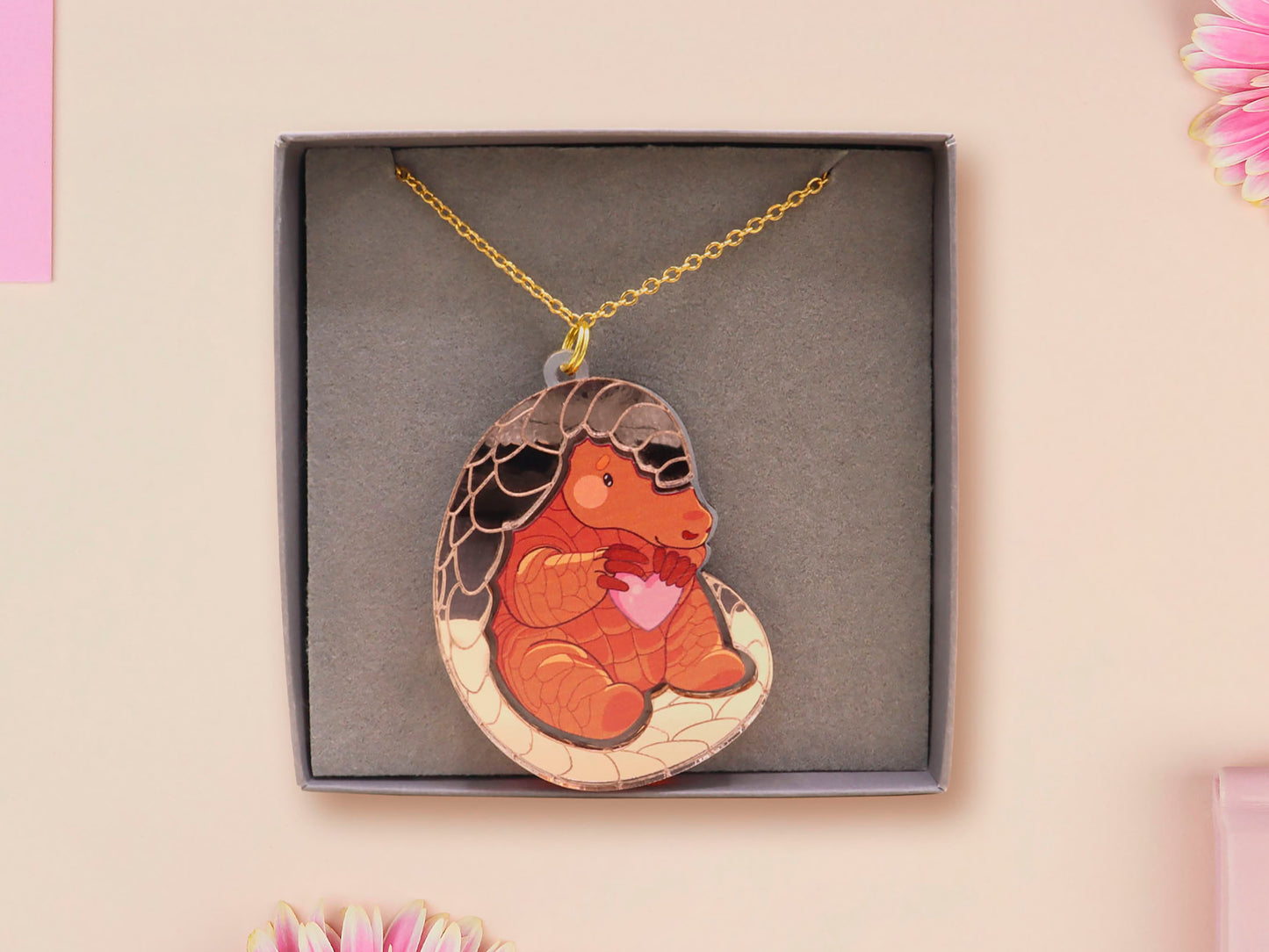 An adorable shy pangolin aardvark holding a heart necklace made of wood and glitter mirror acrylic with a gold chain is displayed in a velvet gift box with a unique cute Pangolin sleeve design.