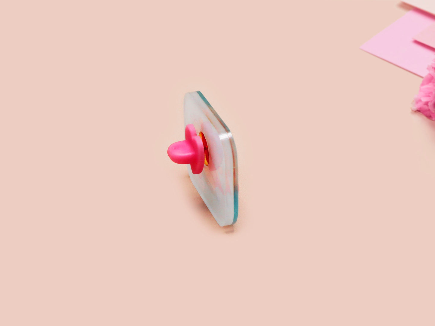 A clear acrylic pin badge with a pink heart-shaped pin back clasp. The design of the pin badge is of a cute relaxing capybara in water with a face mask with the quote don't worry be cappy.