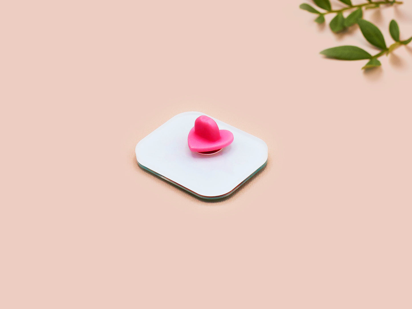 A clear acrylic pin badge with a pink heart-shaped pin back clasp. The design of the pin badge is of a cute relaxing capybara in water with a face mask with the quote don't worry be cappy.