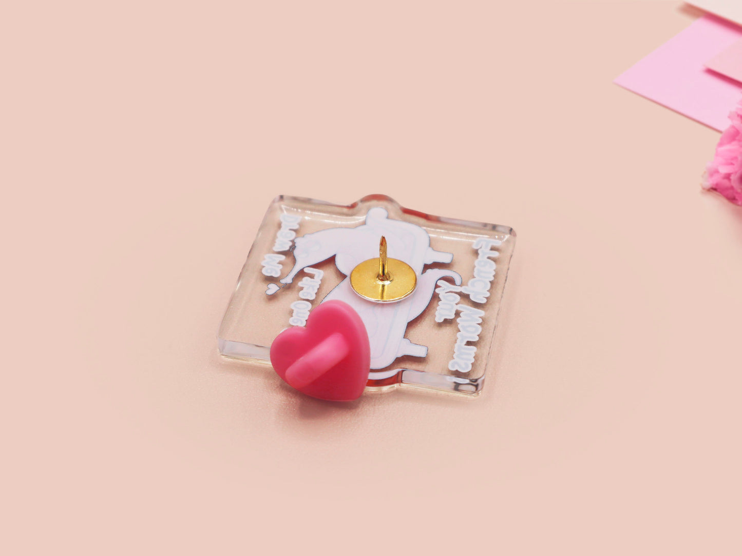 A cute transparent acrylic pin badge with a pink heart-shaped rubber clasp pin back. The design of the pin badge is a cartoon orange worm on a sting sitting on a sofa chaise lounge with the titanic quote Draw Me Like One of Your French Worms