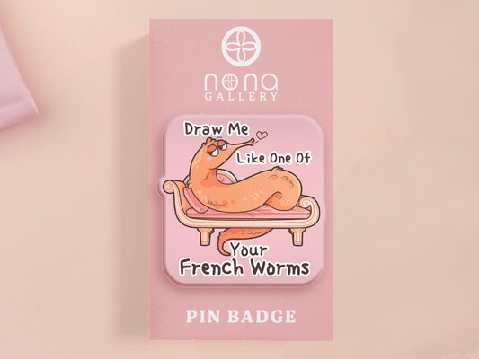A cute transparent acrylic pin badge with a pink heart-shaped rubber clasp pin back. The design of the pin badge is a cartoon orange worm on a sting sitting on a sofa chaise lounge with the titanic quote Draw Me Like One of Your French Worms