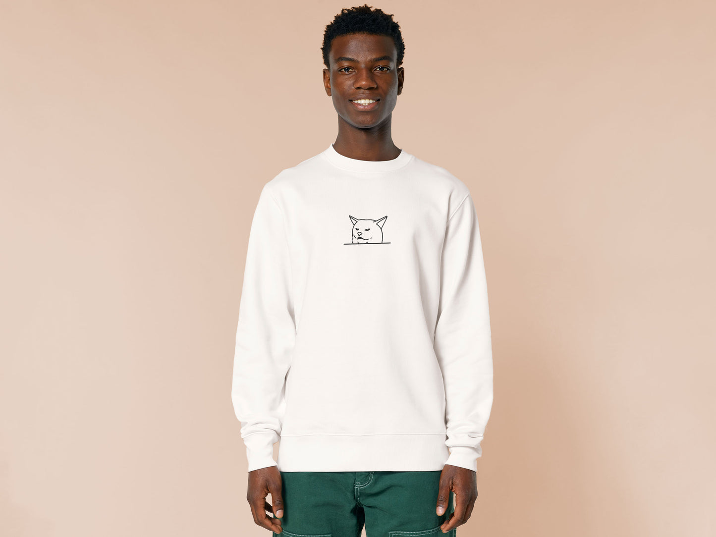 An off-white crew neck long sleeve sweater, with an embroidered black thread design of cute smudge the hissing cat meme reaction