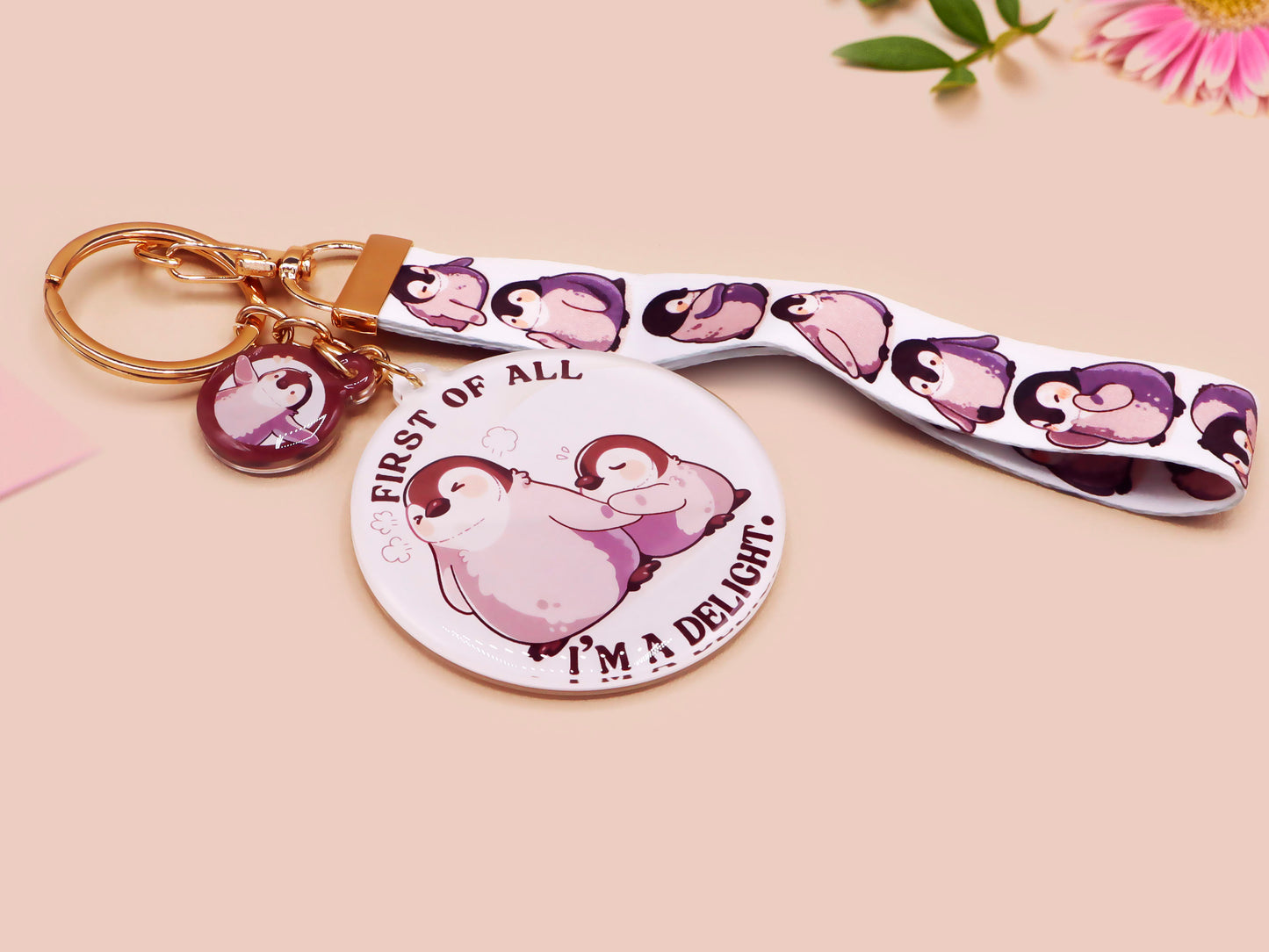 Acrylic epoxy baby penguin keychain with a large acrylic charm of two baby penguins with the quote first of all I'm a delight, a smaller charm of a cute penguin and a matching baby emperor penguin lanyard.