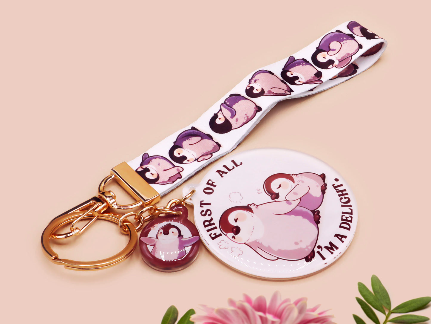 Acrylic epoxy baby penguin keychain with a large acrylic charm of two baby penguins with the quote first of all I'm a delight, a smaller charm of a cute penguin and a matching baby emperor penguin lanyard.
