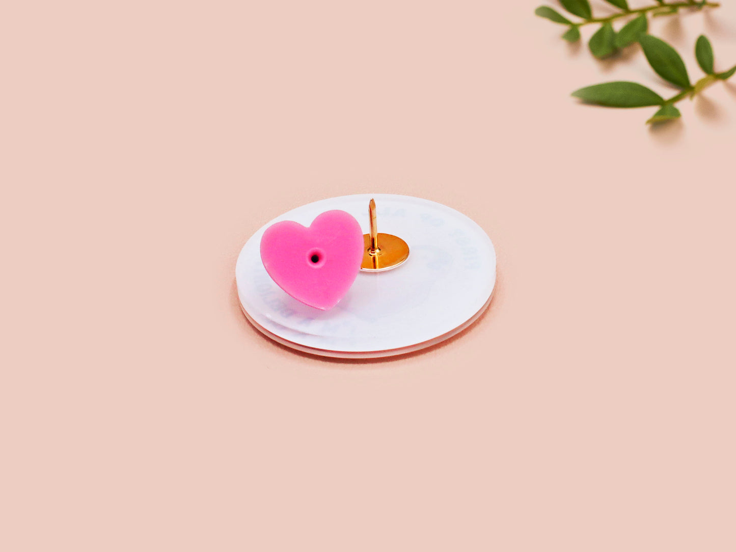 A clear acrylic pin badge with a pink heart-shaped pin back clasp. The design of the pin badge is of a cute baby penguin chicks squabbling with the quote first of all I'm a delight.