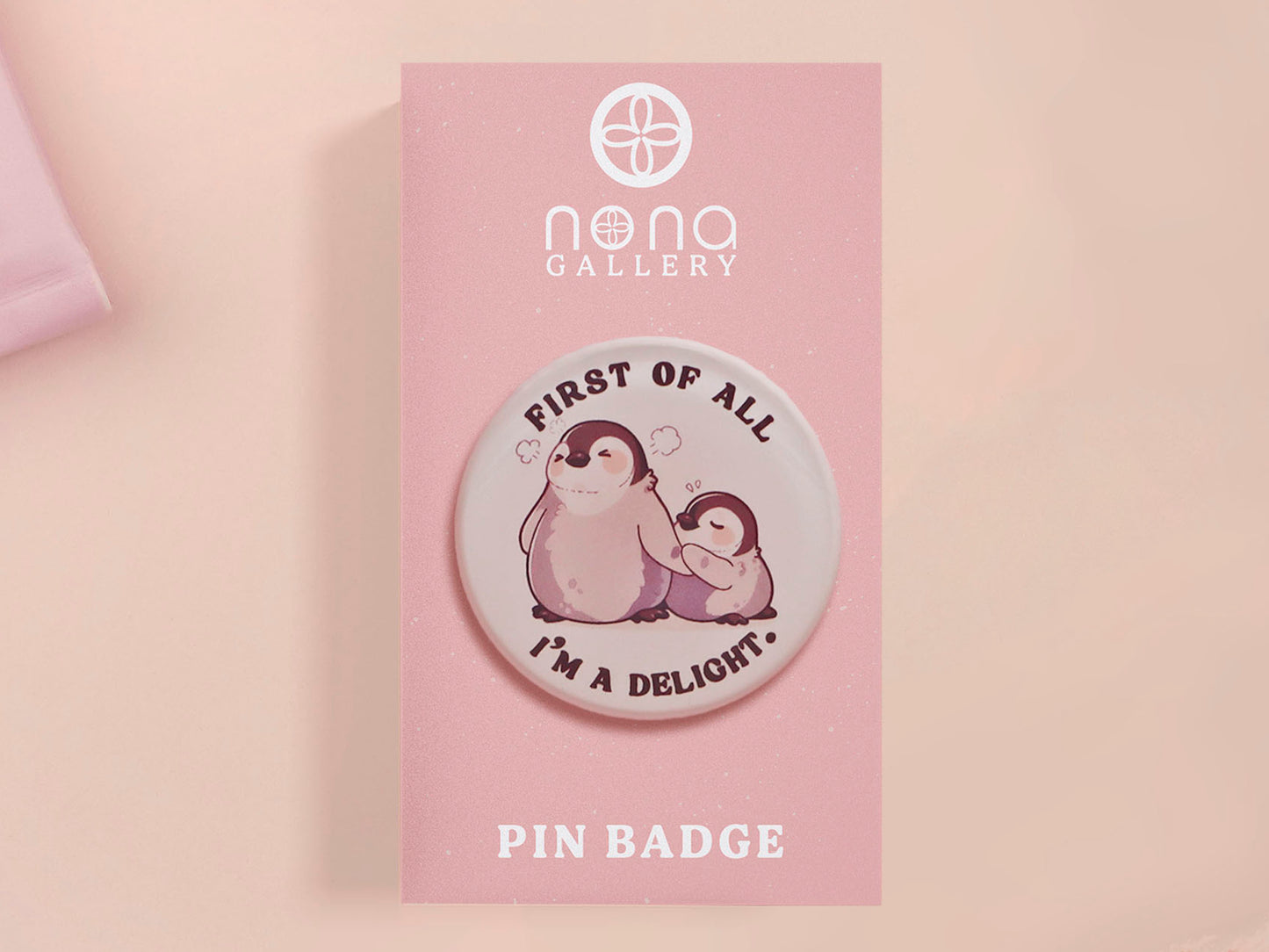 A clear acrylic pin badge with a pink heart-shaped pin back clasp. The design of the pin badge is of a cute baby penguin chicks squabbling with the quote first of all I'm a delight.