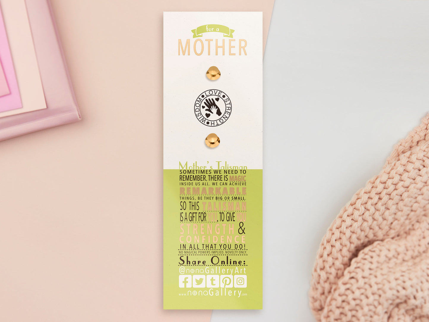 The back of the long white and greens backing card with gold accents. The backing card details the symbolism of the different design elements of the Mothers Talisman pin. Also shown is the two gold locking pin backs attached to the card.