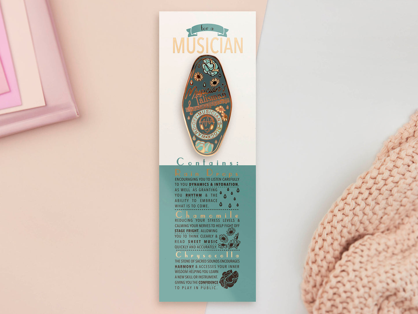 Gold Enamel Talisman Pin with blue design and the words Musician's Talisman sits on a long white and blue backing card with gold accents. The backing card has details the symbolism of the different design elements of the Talisman pin.