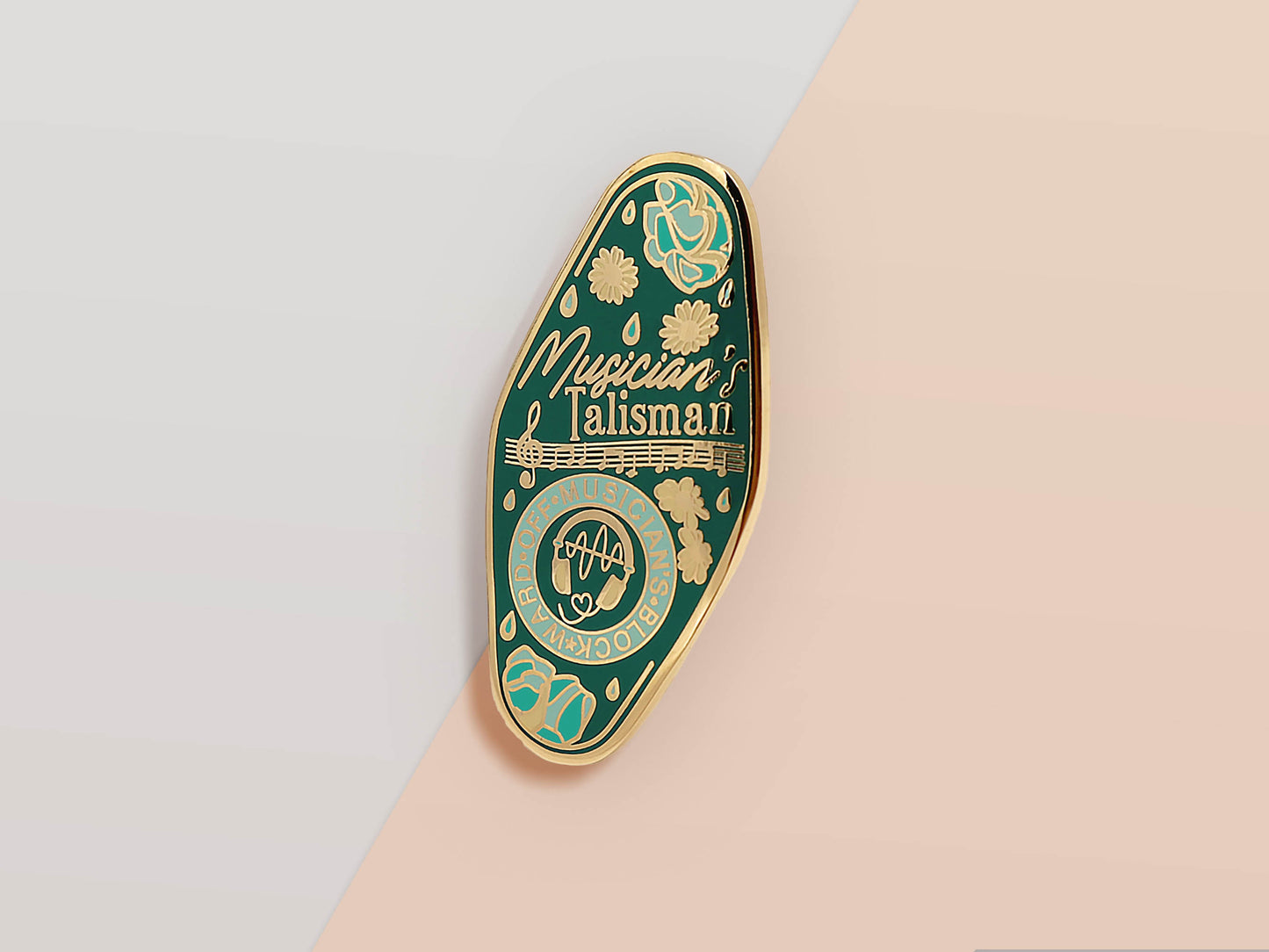 Gold Enamel Talisman Pin with blue design and the words Musician's Talisman, Ward of Musician's block. The pins design includes headphones and sheet music, raindrops, as well as flowers and crystals.