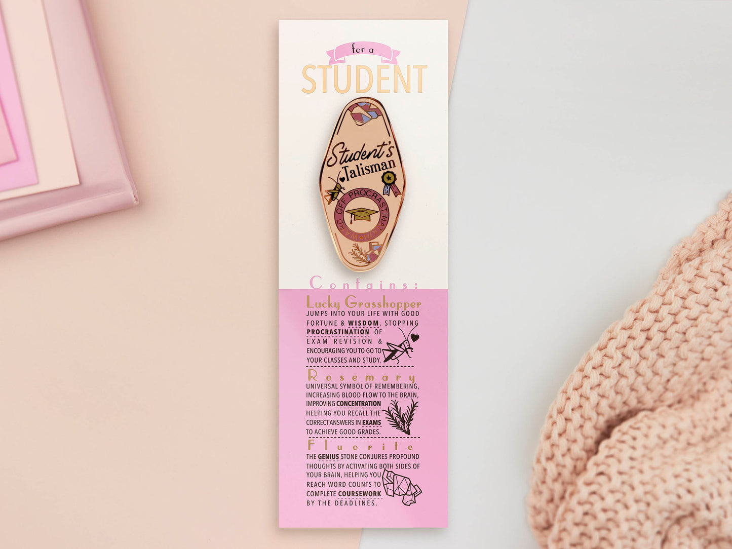 Gold Enamel Talisman Pin with white design and the words Student's Talisman sits on a long white and pink backing card with gold accents. The backing card has details the symbolism of the different design elements of the Talisman pin.