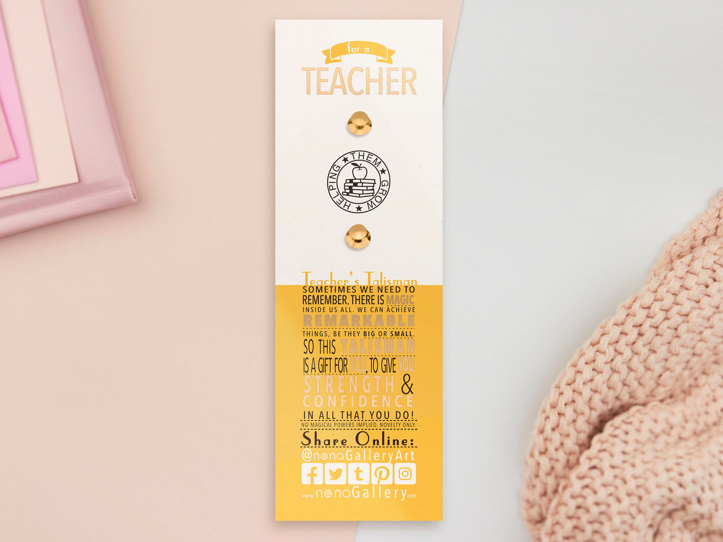 The back of the long white and yellow backing card with gold accents. The backing card details the symbolism of the different design elements of the Teacher's Talisman pin. Also shown is the two gold locking pin backs attached to the card.