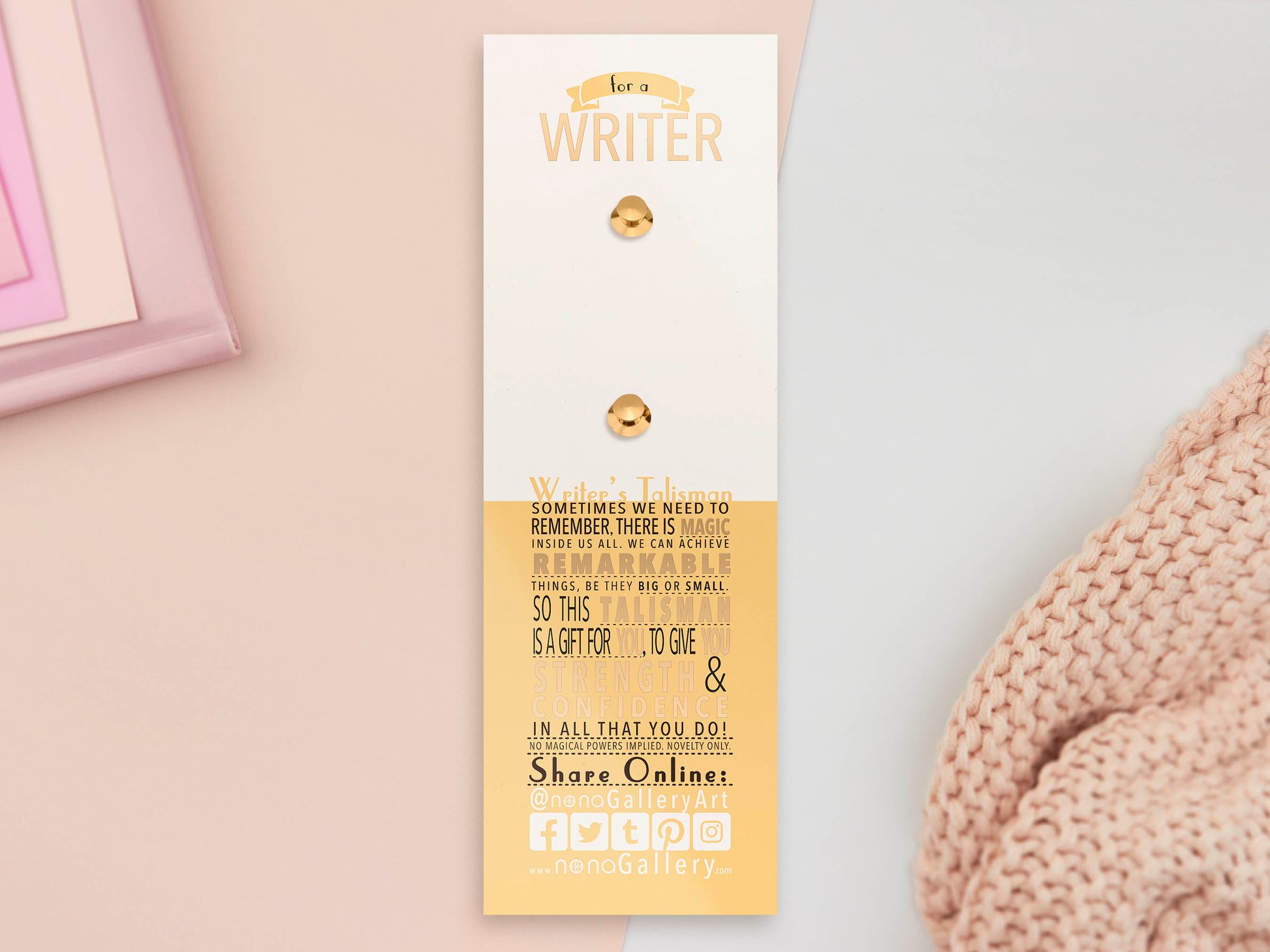 The back of the long white and yellow backing card with gold accents. The backing card details the symbolism of the different design elements of the Writer's Talisman pin. Also shown is the two gold locking pin backs attached to the card.