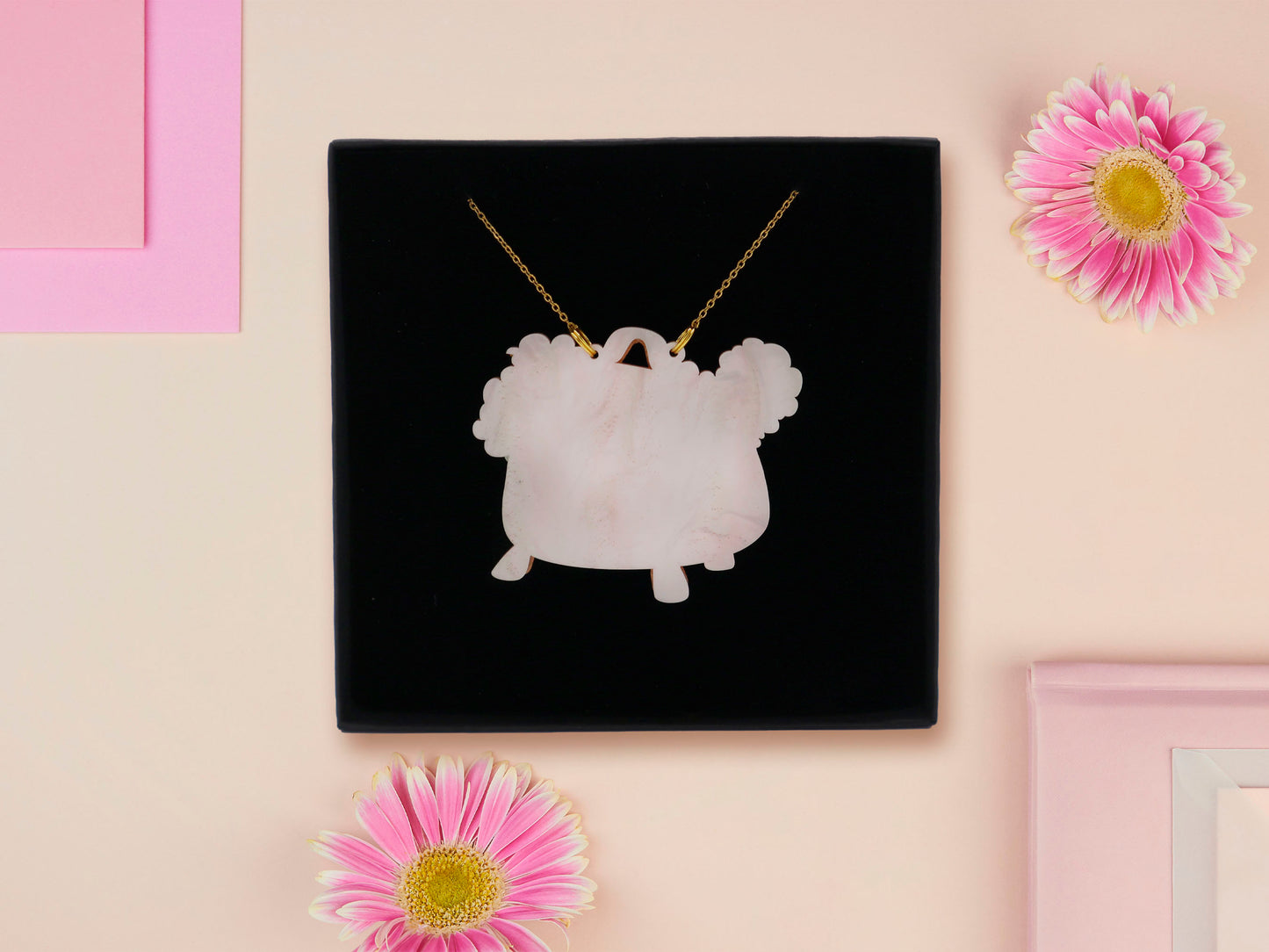 Mixed material handmade necklace of chibi cartoon frog sat inside a bubbling pearlescent witch's cauldron, with a gold chain and black gift box.