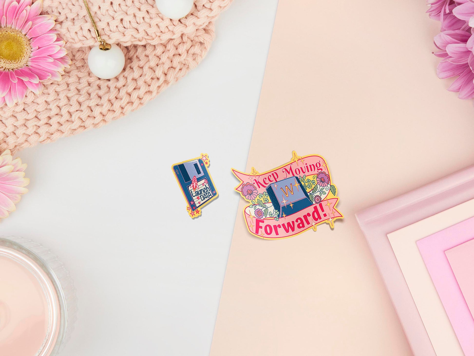 Two peelable stickers, the first is a flopy disk with the text launch data and small space rocket, the second is a W keyboard key surrounded by a ribbon with the text Keep moving forward.
