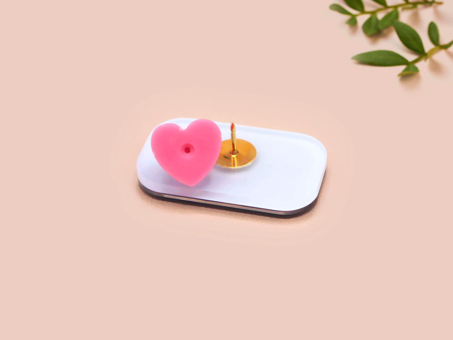 A clear acrylic pin badge with a pink heart-shaped pin back clasp. The design of the pin badge is of a cute chibi penguin dancing in a suit under a spotlight with the quote give 'em the ol' razzle dazzle