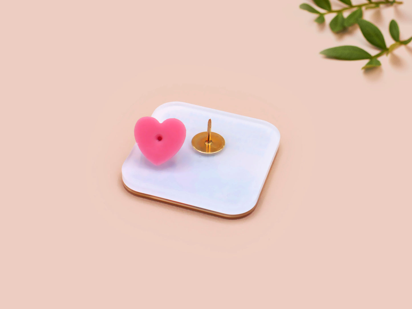 A clear acrylic pin badge with a pink heart-shaped pin back clasp. The design of the pin badge is of a cute chibi blue godzilla like kaiju destroying a city with the quote I Think I Smash Buildings Because My Father Was Distant.