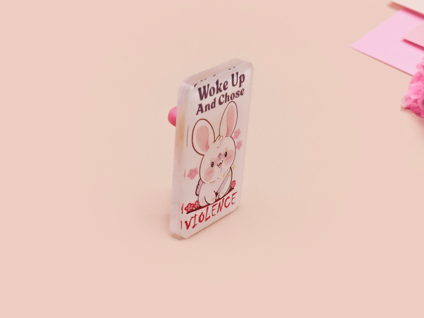 Clear acrylic pin badge with pink heart-shaped rubber pin back clasp. The design of the pin badge is a cute cartoon chibi white rabbit with the quote Woke Up And Chose Violence.