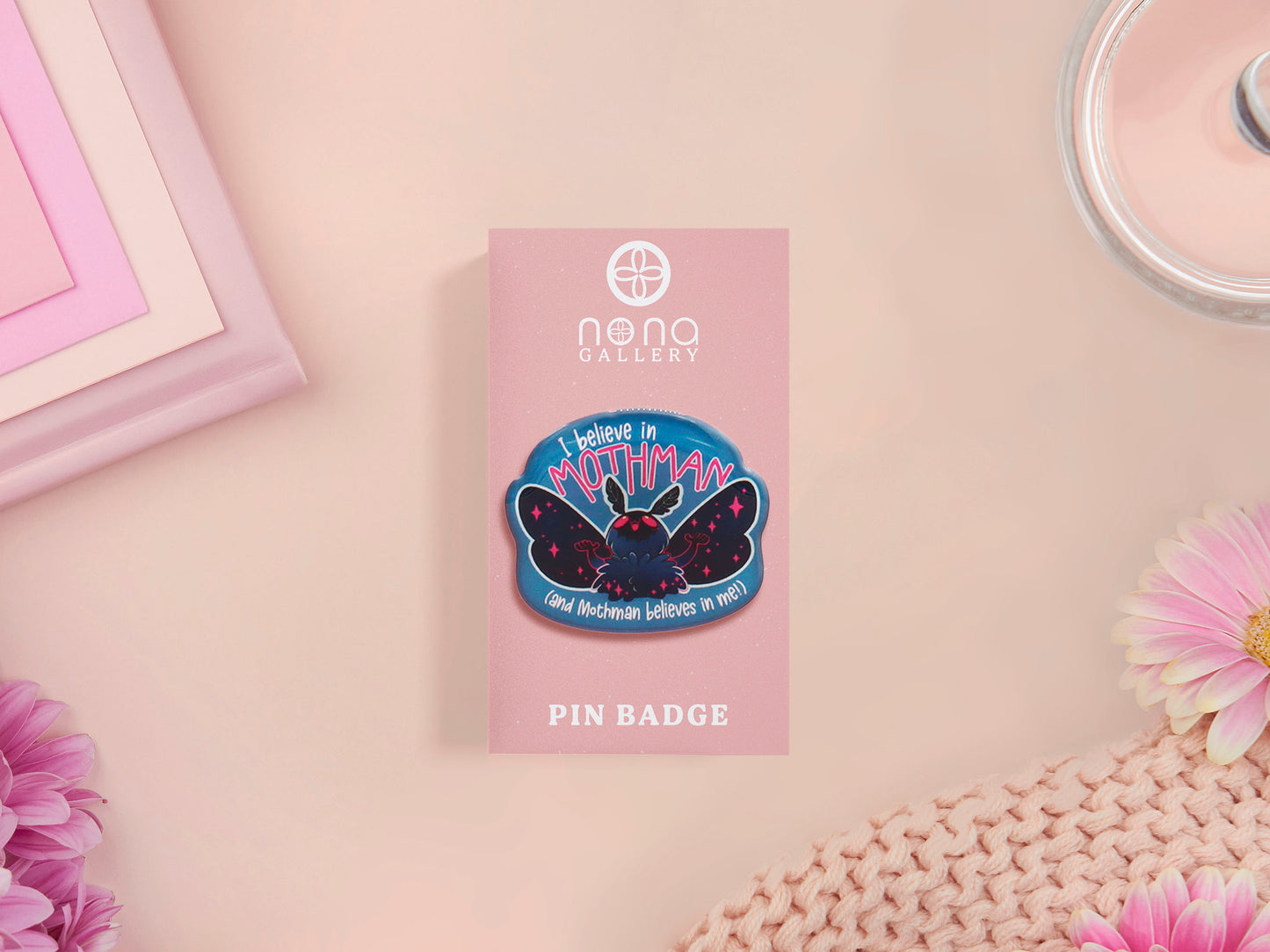 Clear acrylic pin badge with pink heart-shaped rubber pin back clasp. The design of the pin badge is a cute cartoon chibi Mothman cryptid with the quote I believe in Mothman and Mothman believes in me.