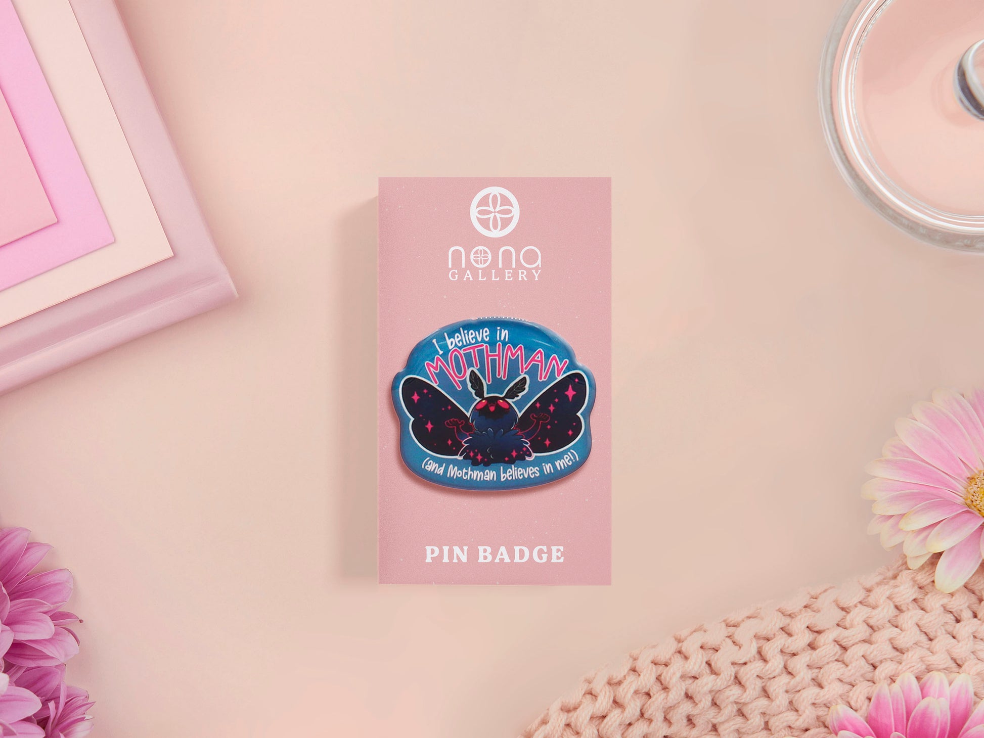Clear acrylic pin badge with pink heart-shaped rubber pin back clasp. The design of the pin badge is a cute cartoon chibi Mothman cryptid with the quote I believe in Mothman and Mothman believes in me.