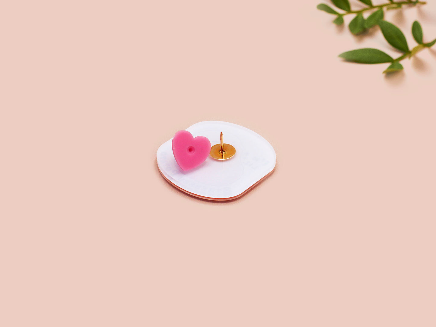 A clear acrylic pin badge with a pink heart-shaped pin back clasp. The design of the pin badge is of a cute chibi potato with the quote I'm a lil' stressed potato