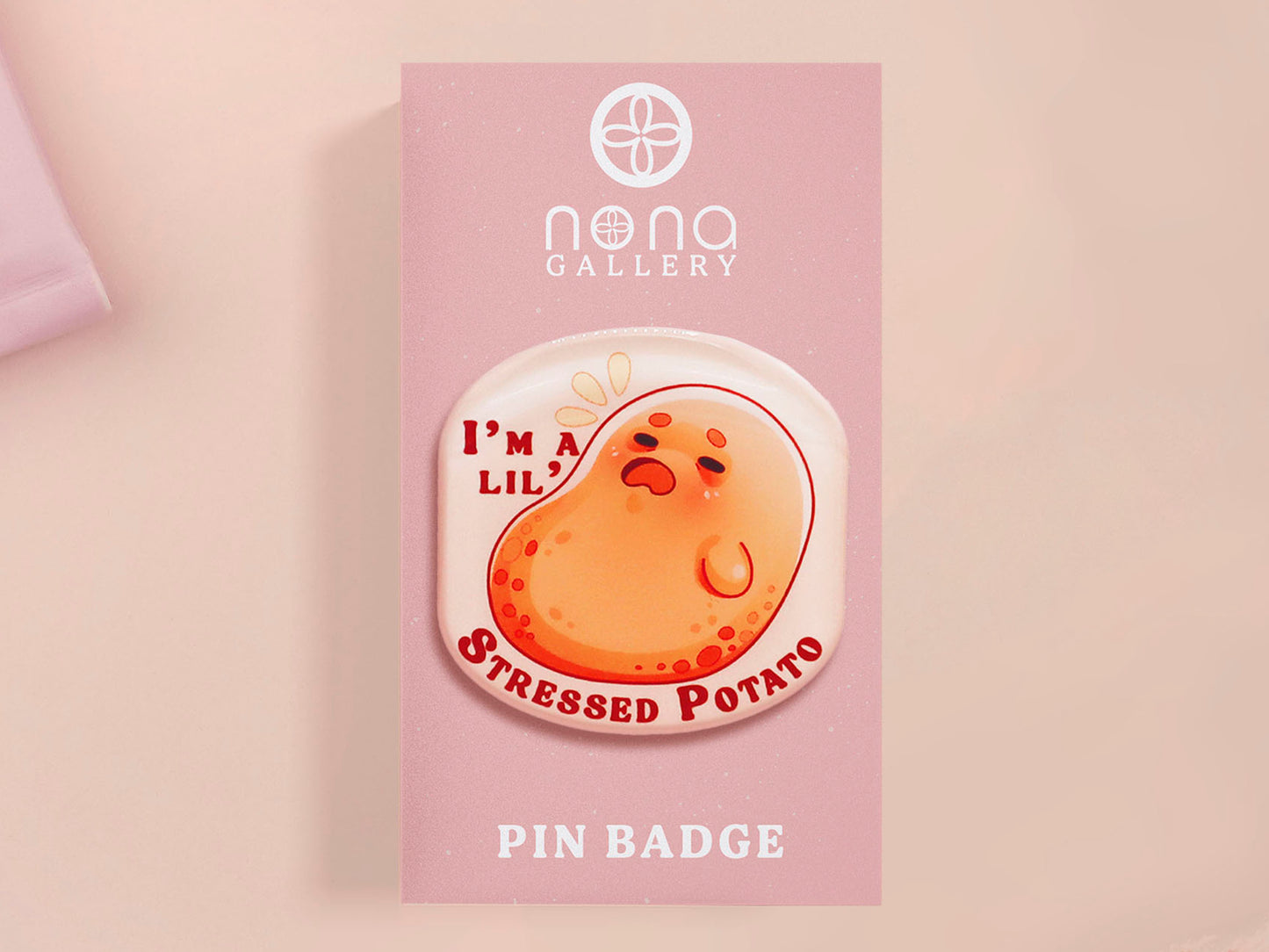 A clear acrylic pin badge with a pink heart-shaped pin back clasp. The design of the pin badge is of a cute chibi potato with the quote I'm a lil' stressed potato