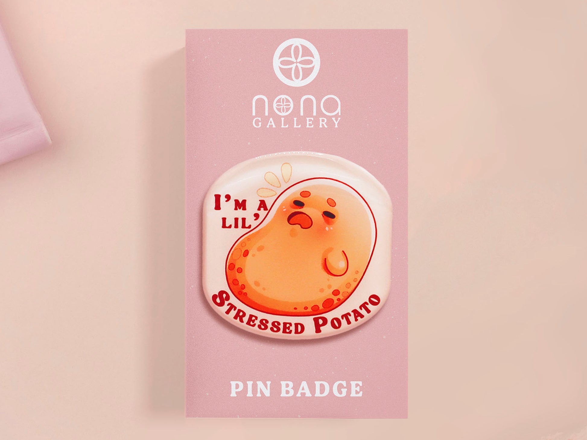 A clear acrylic pin badge with a pink heart-shaped pin back clasp. The design of the pin badge is of a cute chibi potato with the quote I'm a lil' stressed potato