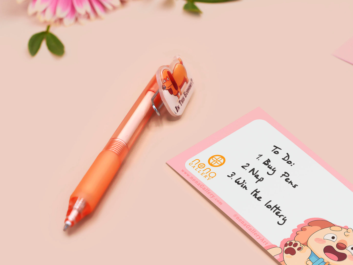 Orange ballpoint pen with black ink and a cute chibi dachshund sausage dog design.