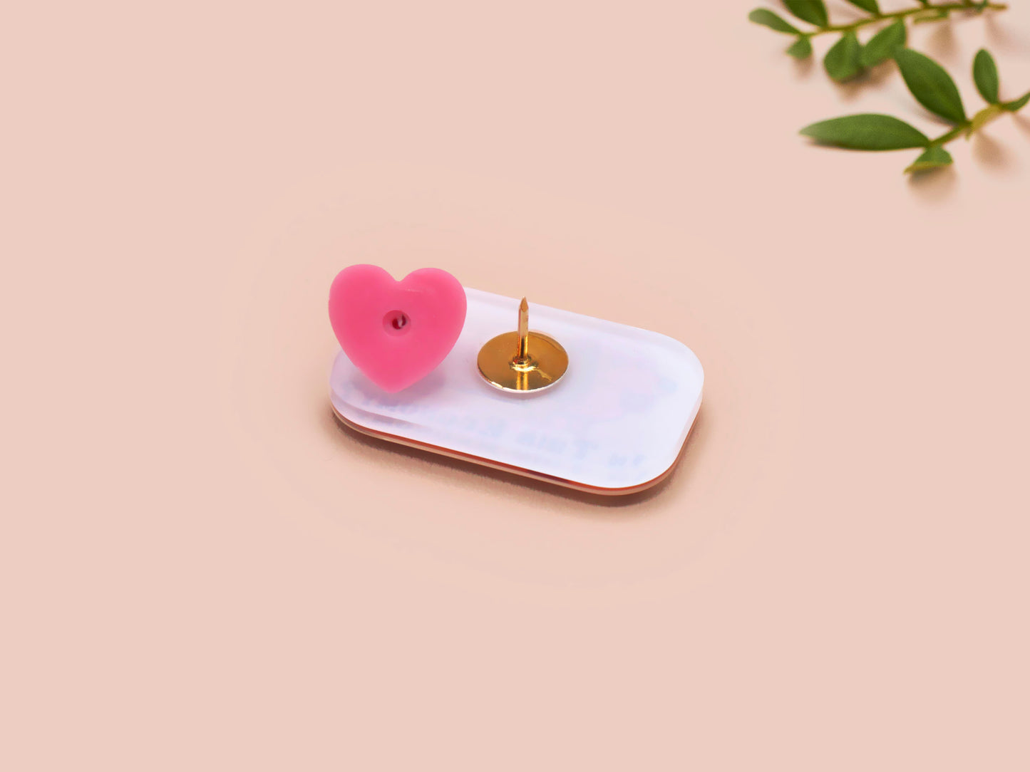 A clear acrylic pin badge with a pink heart-shaped pin back clasp. The design of the pin badge is of a cute chibi dachshund sausage dog with the quote in this economy?