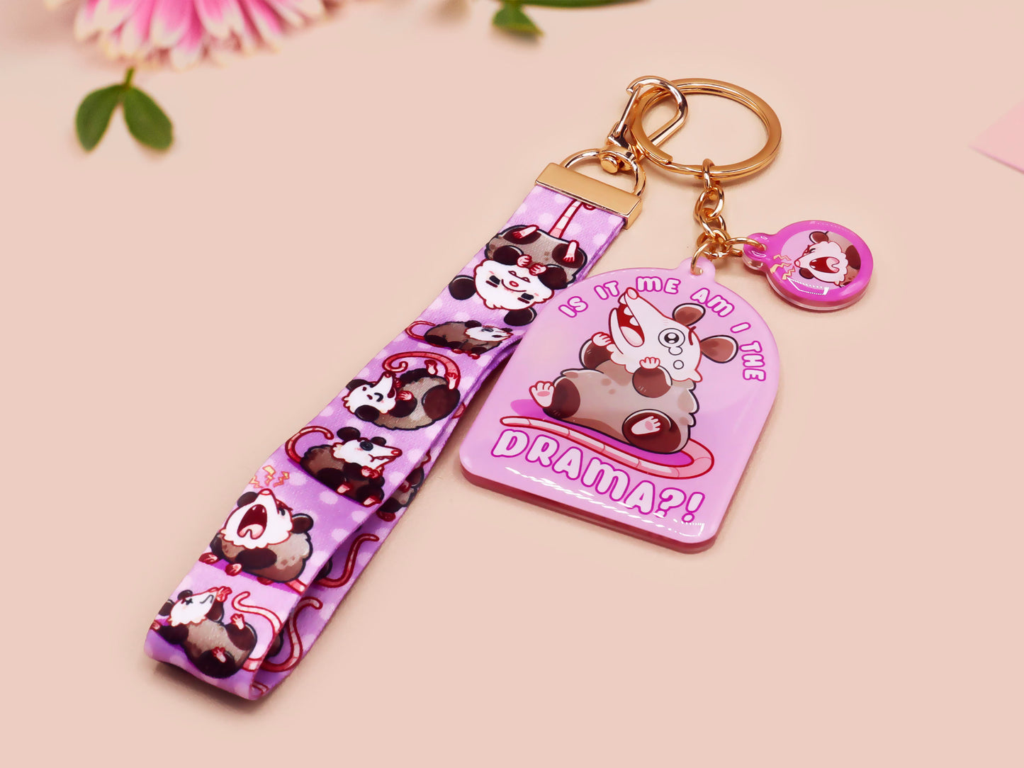 Acrylic epoxy possum keychain with a large acrylic charm of a purple screaming possum with the quote is it me am I the drama, a smaller charm of a cute crying possum and a matching purple possum lanyard.