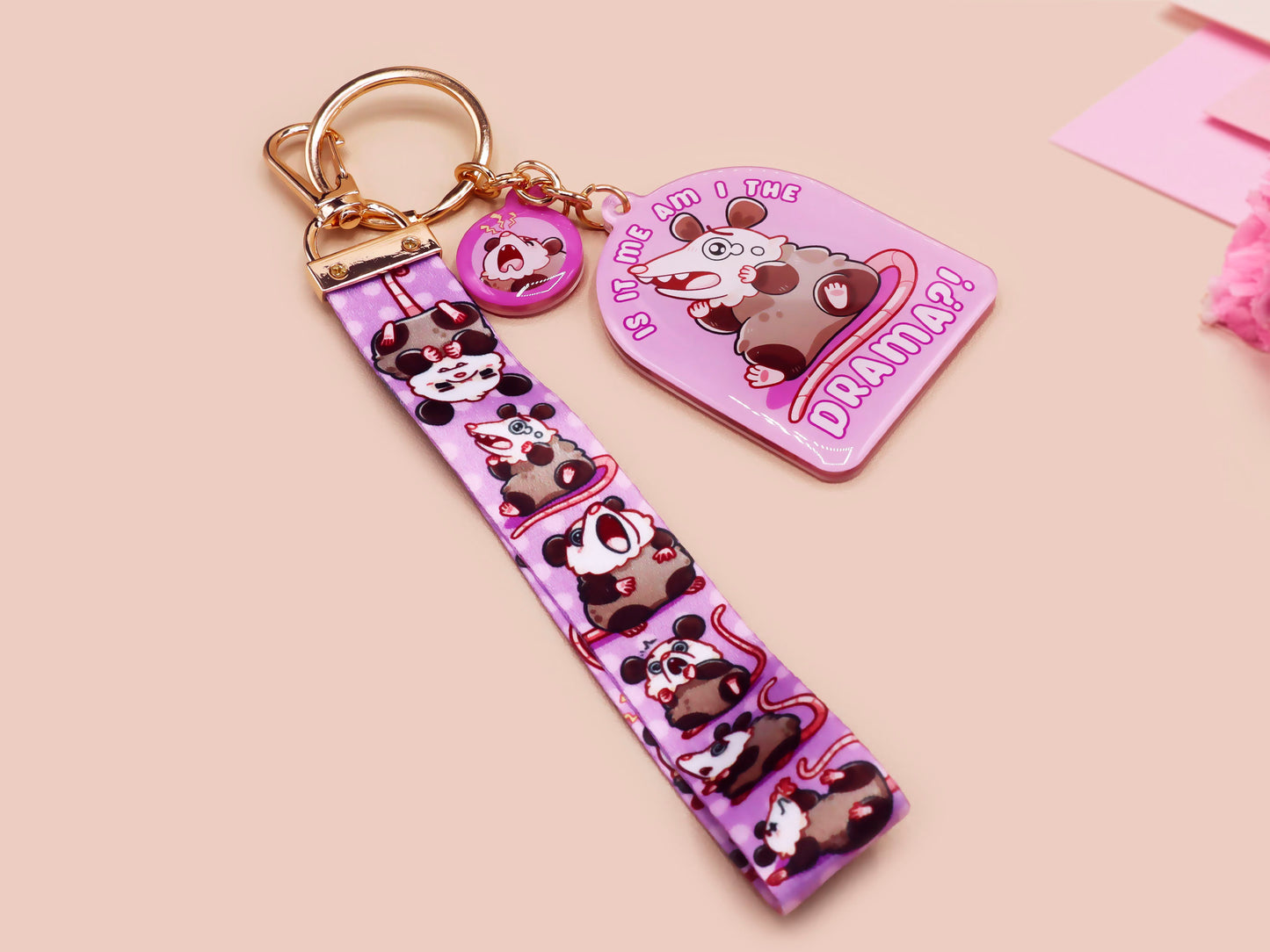 Acrylic epoxy possum keychain with a large acrylic charm of a purple screaming possum with the quote is it me am I the drama, a smaller charm of a cute crying possum and a matching purple possum lanyard.