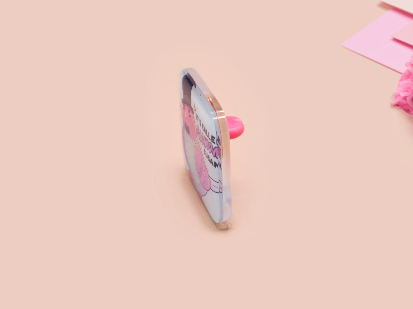 A clear acrylic pin badge with a pink heart-shaped pin back clasp. The design of the pin badge is of a cute chibi pigeon wearing a top hat with the quoteit's called fashion susan