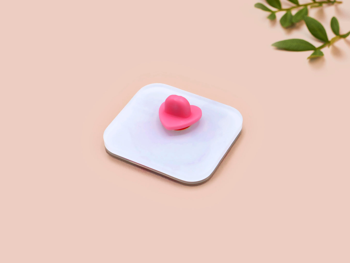 A clear acrylic pin badge with a pink heart-shaped pin back clasp. The design of the pin badge is of a cute chibi pigeon wearing a top hat with the quoteit's called fashion susan