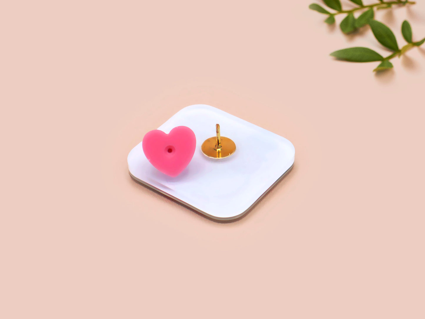 A clear acrylic pin badge with a pink heart-shaped pin back clasp. The design of the pin badge is of a cute chibi pigeon wearing a top hat with the quoteit's called fashion susan