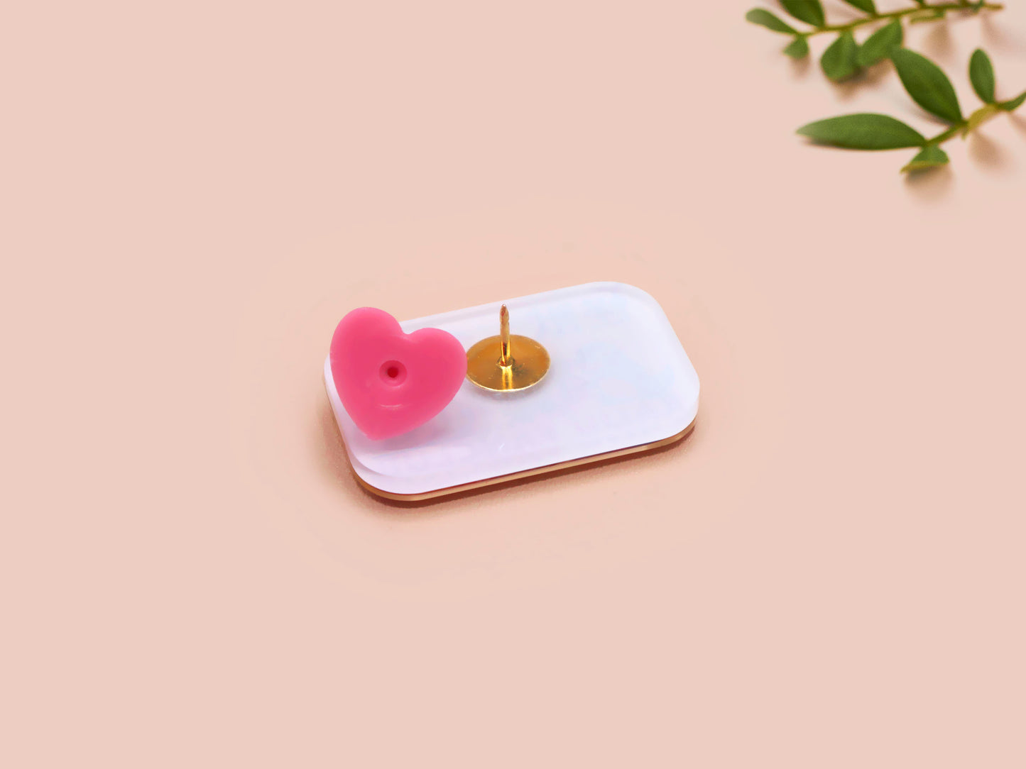 A clear acrylic pin badge with a pink heart-shaped pin back clasp. The design of the pin badge is of a cute chibi blue godzilla like kaiju mothra and King Ghidorah destroying a city with the quote kaiju fanclub and kaiju warning in japanese kanji