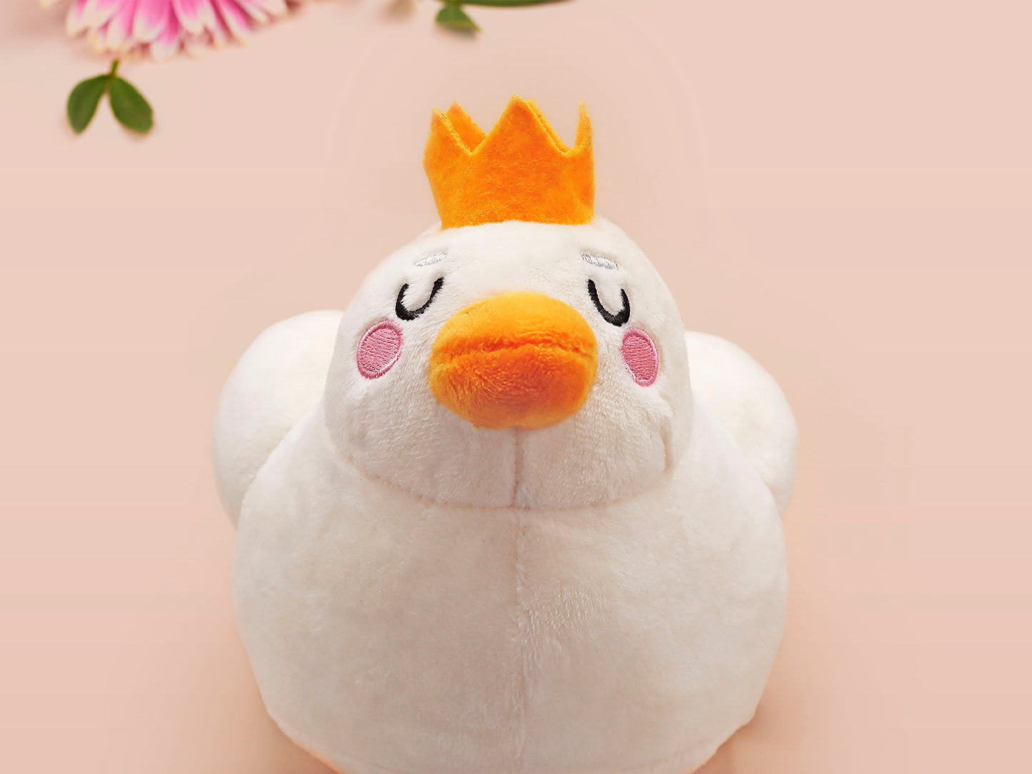 An adorable white duck bird plushie toy with cute embroidered eyes and facial expression, wearing a yellow crown hat, with a hang tag describing the duck as King Larry.