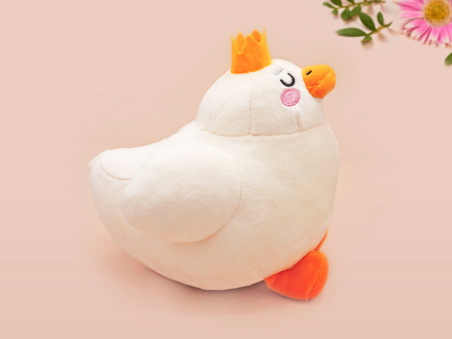 An adorable white duck bird plushie toy with cute embroidered eyes and facial expression, wearing a yellow crown hat, with a hang tag describing the duck as King Larry.