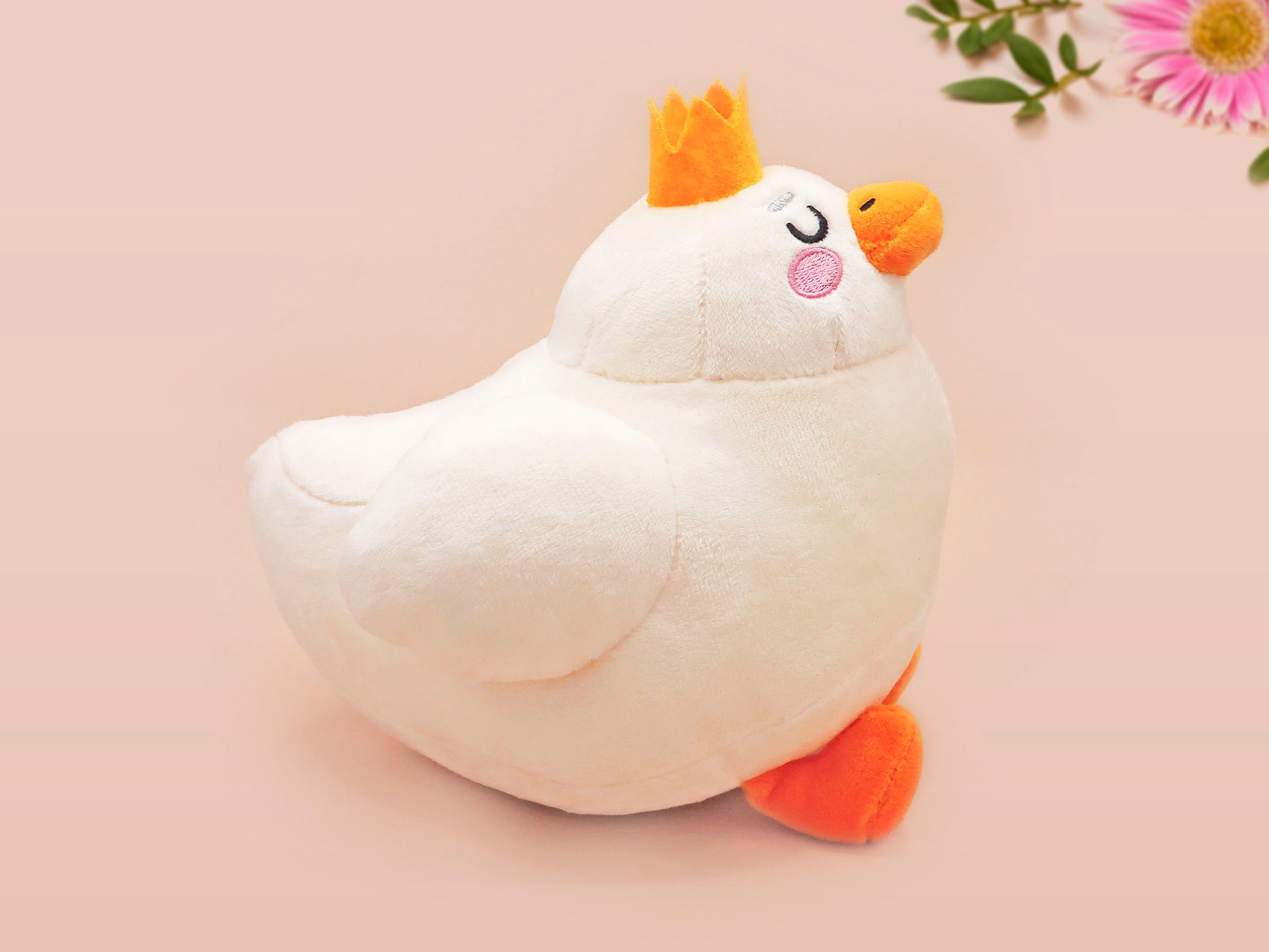 An adorable white duck bird plushie toy with cute embroidered eyes and facial expression, wearing a yellow crown hat, with a hang tag describing the duck as King Larry.