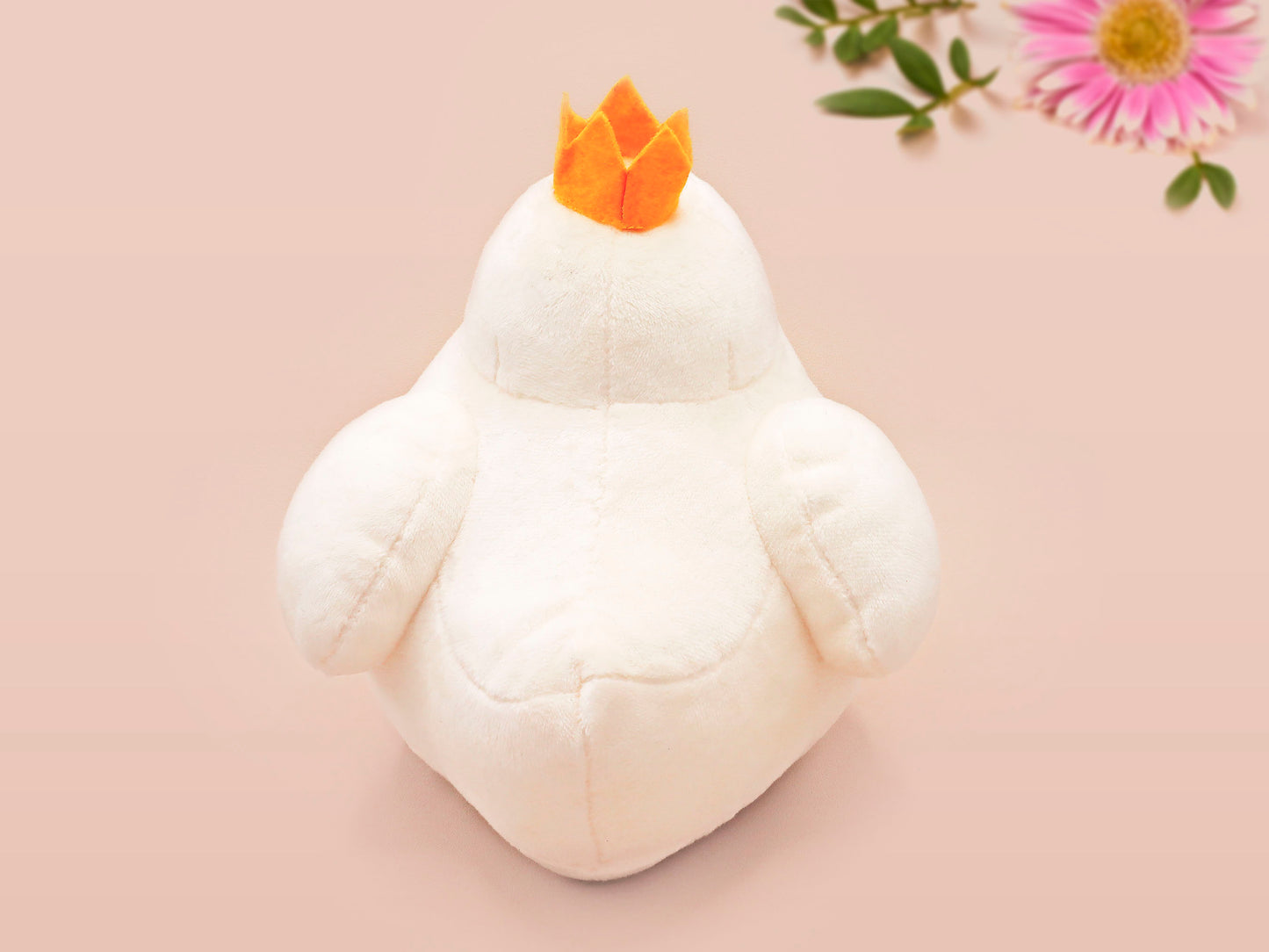 An adorable white duck bird plushie toy with cute embroidered eyes and facial expression, wearing a yellow crown hat, with a hang tag describing the duck as King Larry.