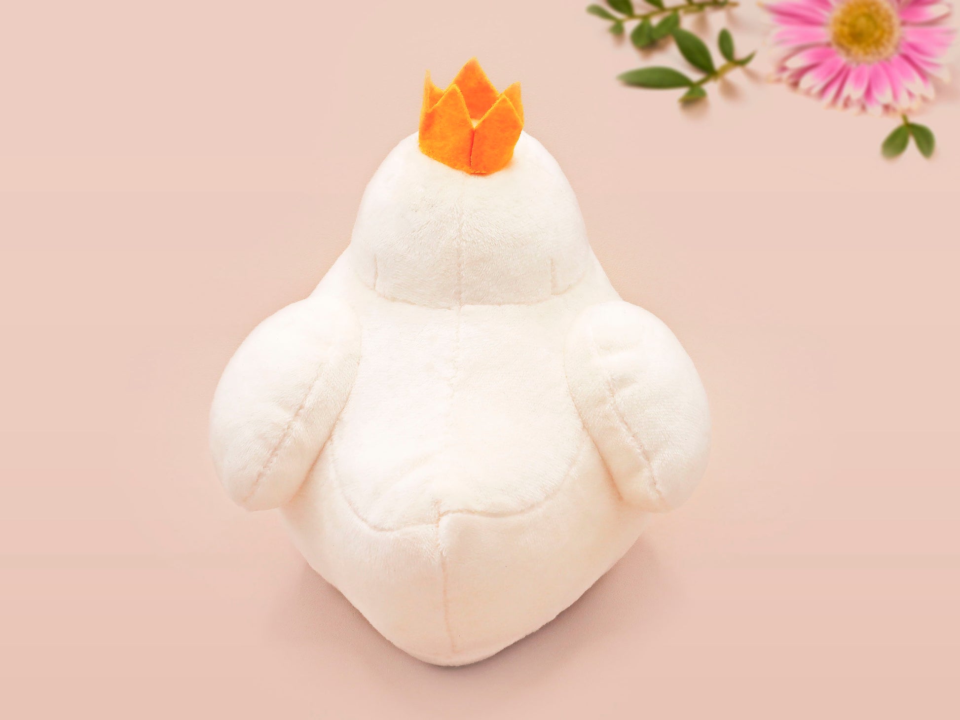 An adorable white duck bird plushie toy with cute embroidered eyes and facial expression, wearing a yellow crown hat, with a hang tag describing the duck as King Larry.