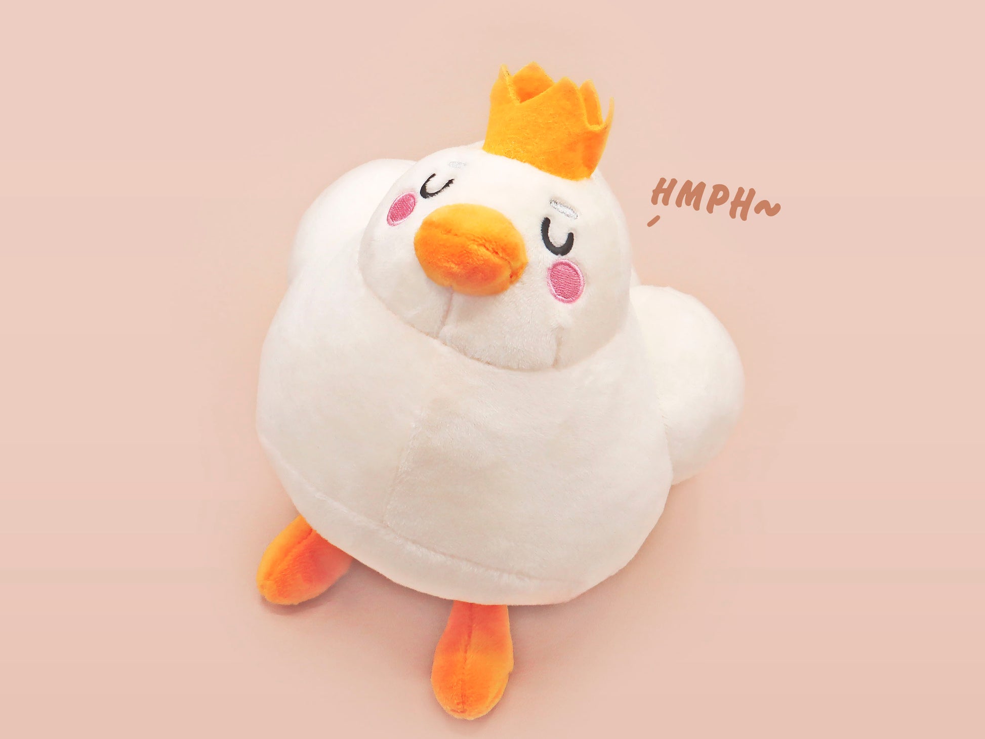 An adorable white duck bird plushie toy with cute embroidered eyes and facial expression, wearing a yellow crown hat, with a hang tag describing the duck as King Larry.