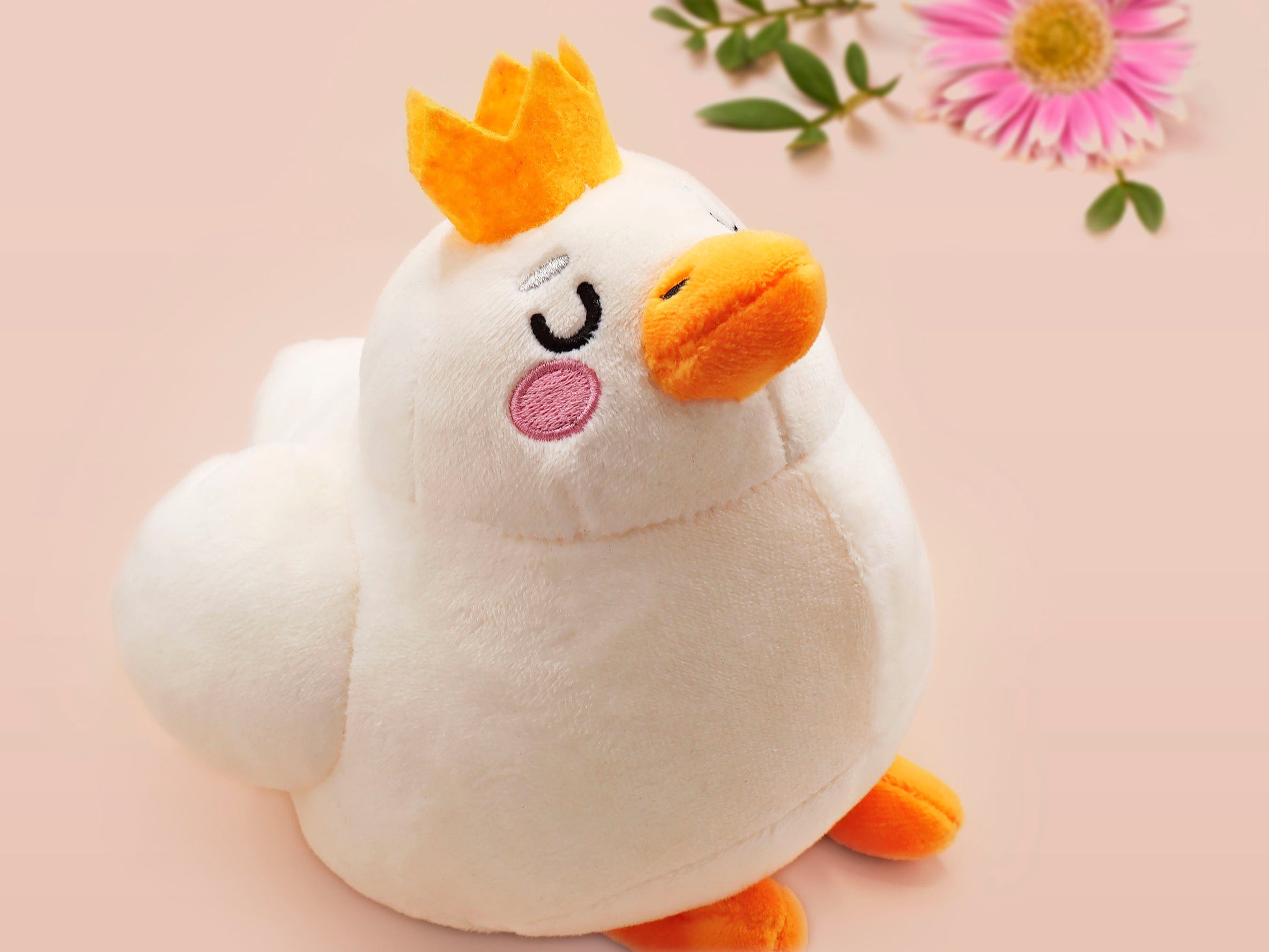 An adorable white duck bird plushie toy with cute embroidered eyes and facial expression, wearing a yellow crown hat, with a hang tag describing the duck as King Larry.