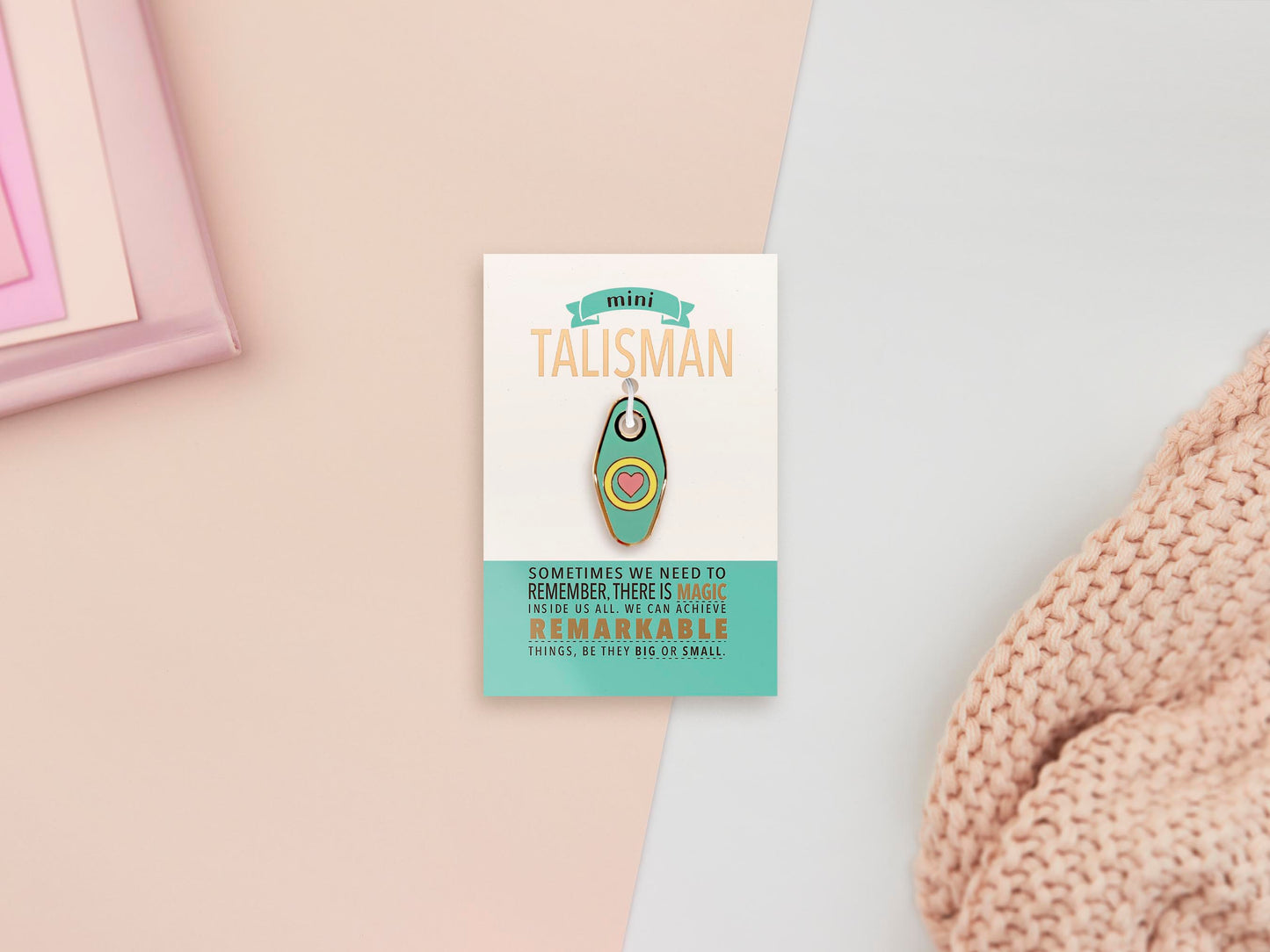 Gold Enamel Talisman Charm the words Mini Talisman sits on a long white and green backing card with gold accents. The backing card has details the symbolism of the different design elements of the Talisman pin.